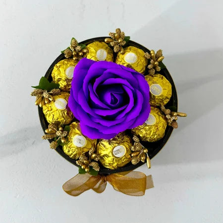 Blumenarrangement mit einer Seifenrose, goldenen Staubfäden und 8 Ferrero Rocher, schwarze Samtbox, violett