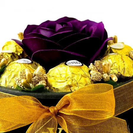 Blumenarrangement mit einer Seifenrose, goldenen Staubblättern und 8 Ferrero Rocher, schwarzer Samtschachtel, violett-burgunderfarben